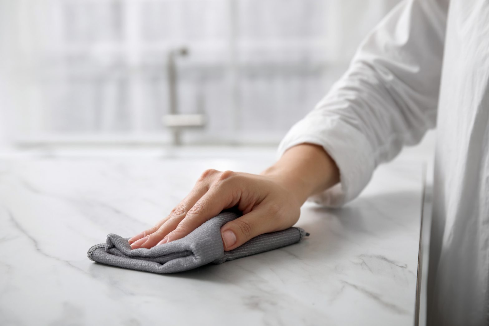 woman wiping marble countertop